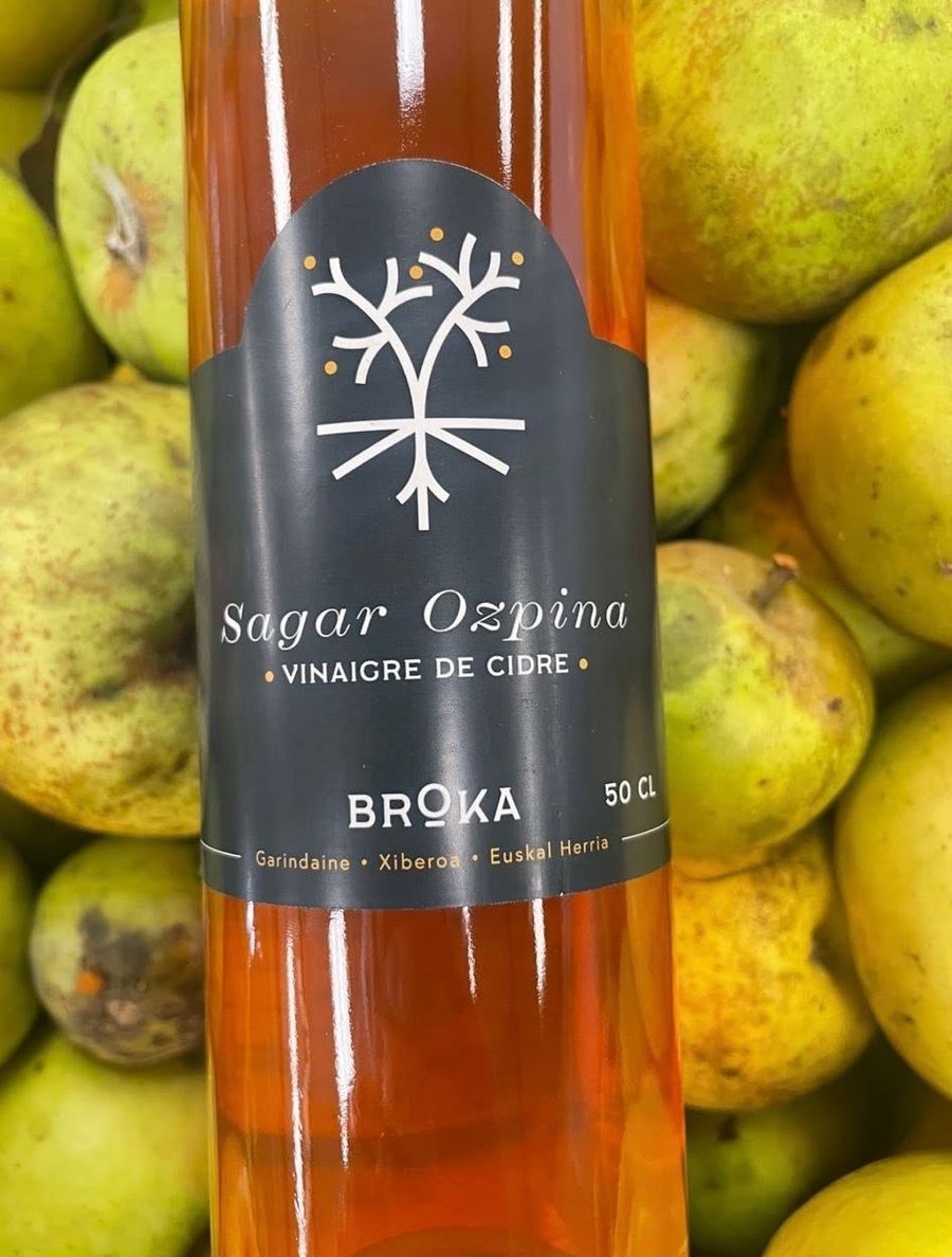 Bouteille Sagar Ozpina 50 cl posée sur les pommes du verger — vinaigre de cidre BIO, Ferme Goyhenetxea, Xiberoa, Pays Basque